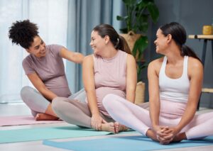 Three happy women in yoga pants sitting on the floor of a maternity home.